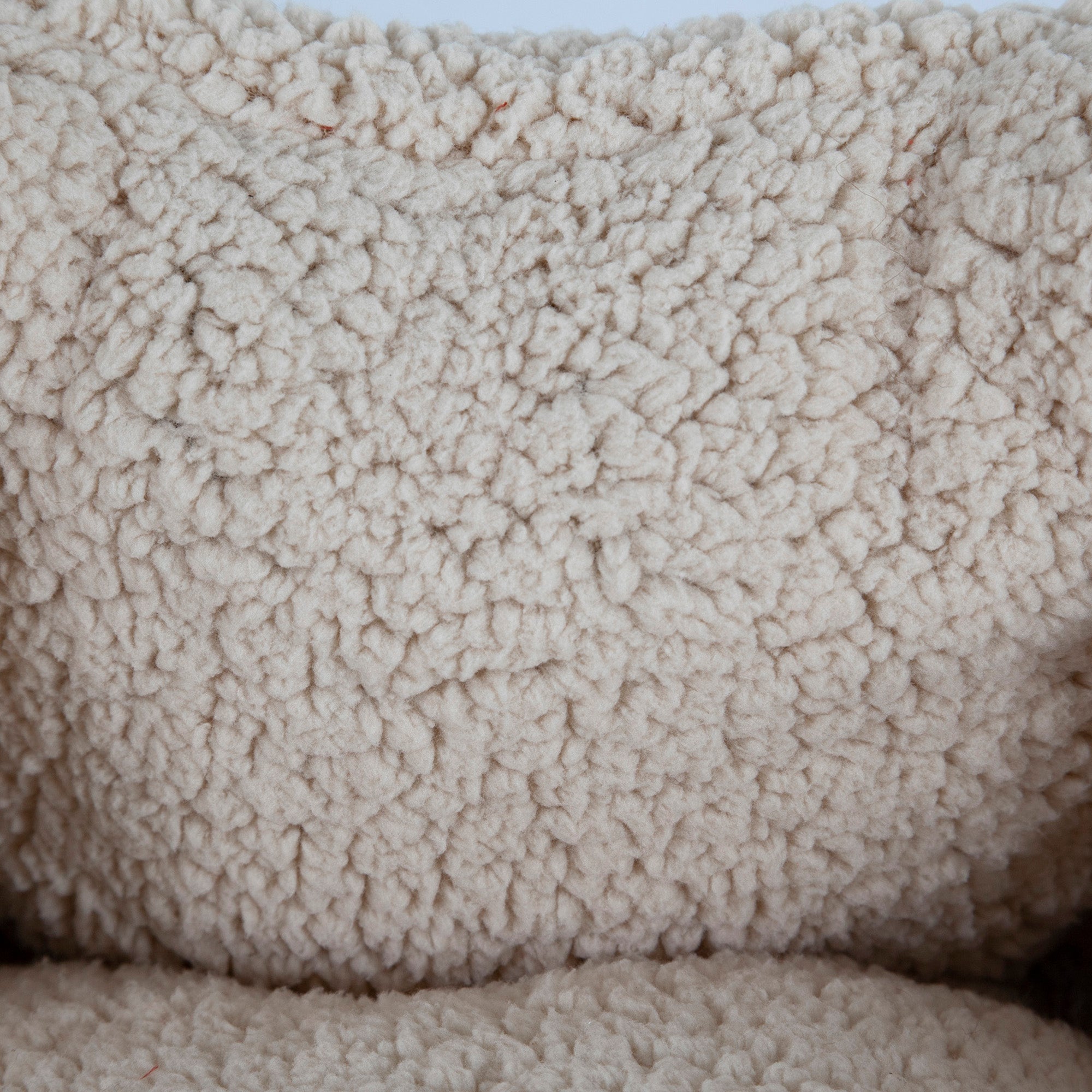 Close-up image of the Aspen Pet Self-Warming Oval Lounger Pet Bed, featuring cream-colored fleece fabric with soft, fluffy wool-like loops for a cozy appearance. Perfect for a stylish and comfortable pet bed crafted to warm your furry friend.