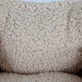 Close-up image of the Aspen Pet Self-Warming Oval Lounger Pet Bed, featuring cream-colored fleece fabric with soft, fluffy wool-like loops for a cozy appearance. Perfect for a stylish and comfortable pet bed crafted to warm your furry friend.