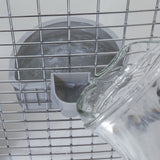 A glass pitcher pours water into the Petmate No Spill Kennel Cup, securely attached to a wire cage interior. The design ensures a smooth flow, efficiently filling the cup for pet hydration.