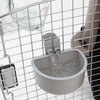 The Petmate No Spill Kennel Cup by Petmate is a gray automatic water dispenser attached to a metal cage, featuring a transparent bottle and dual spouts for spill-proof travel convenience.