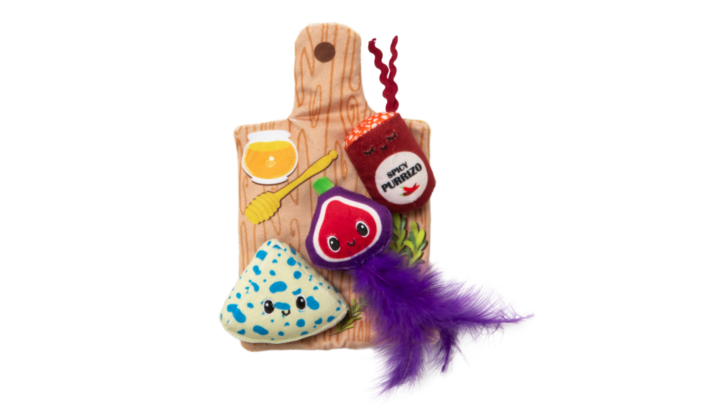 Check out the Quirky Kitty Charcuterie Board Play Mat: a vibrant set with a plush yeast jar, brie wedge, and purple fig. The board has a honey dipper design and is adorned with catnip and a big purple feather for endless feline fun.